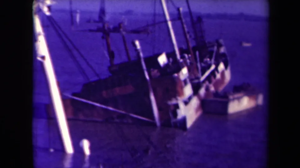 Close 1945 France harbor frame showing the listing vessel from above or dockside, with masts, rigging, and water around the hull.
