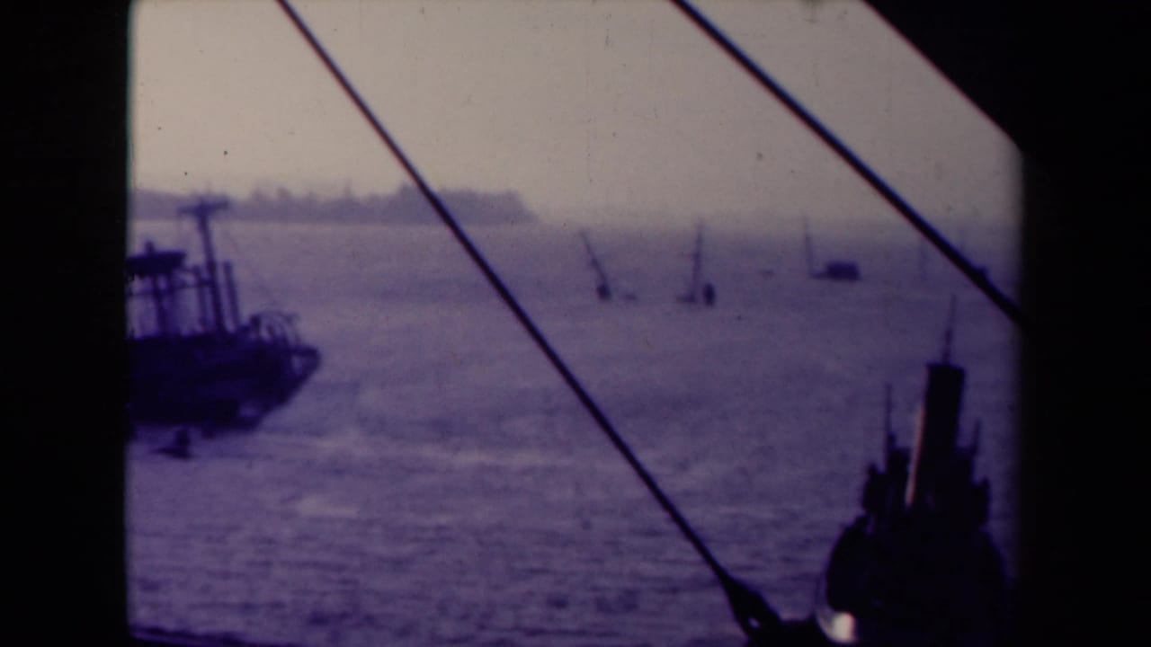 Hazy sea with distant masts and a dark vessel partly framed by ship structure.