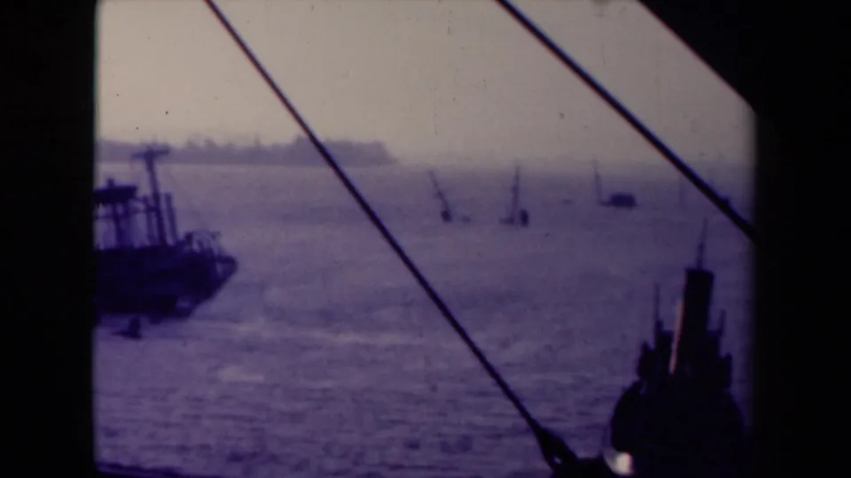 1945 France 8mm view of distant masts or cranes over water, with a dark vessel at left and heavy shipboard framing.