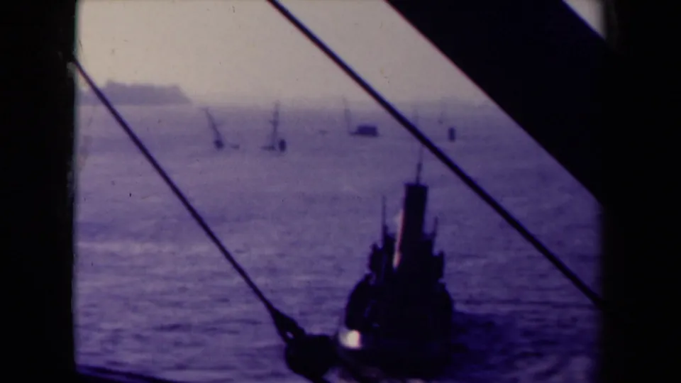 1945 France 8mm maritime view with dark foreground rigging, distant masts or cranes, calm sea, and a faint shoreline.