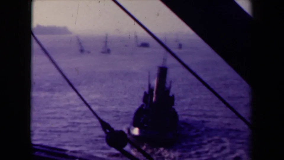 1945 France 8mm frame showing a tugboat moving across water, viewed through dark boat framing and diagonal ropes.