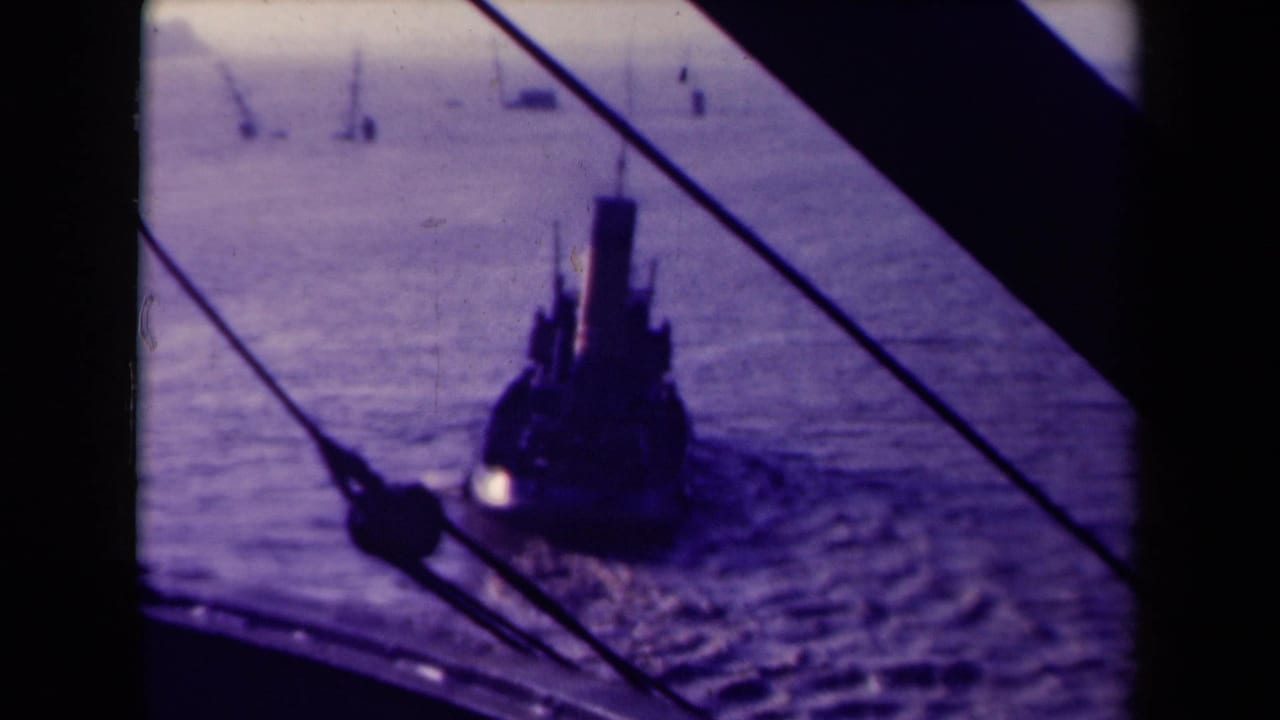 1945 France 8mm view of a tugboat on the water, framed by dark structural edges and rigging, with small vessels in the distance.