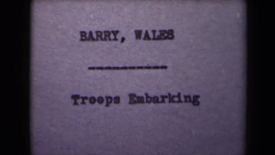 1940s 8mm title card frame showing the same "BARRY, WALES" and "Troops Embarking" wording with visible film grain.
