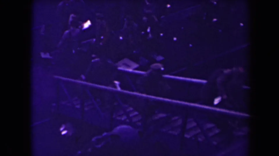 Uniformed men appear to board or gather near a ship rail at night in grainy 8mm footage.