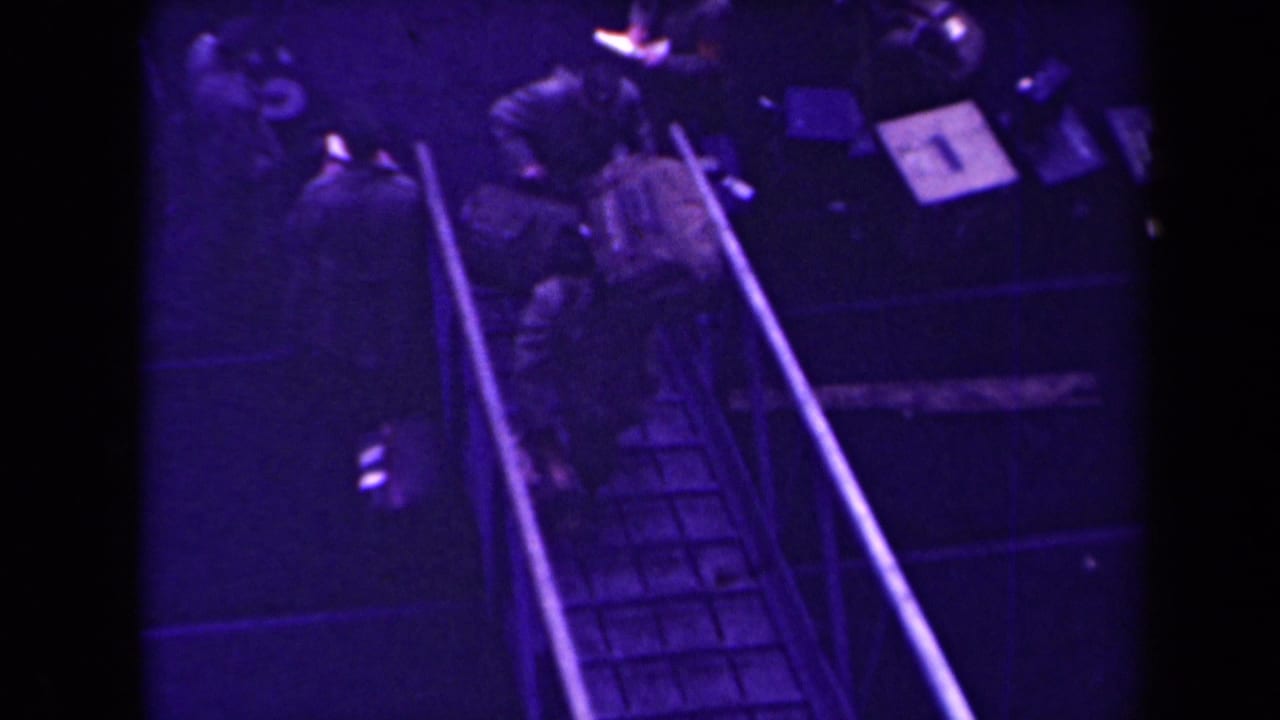 Uniformed soldiers move along a narrow ramp in a dim purple-lit space.