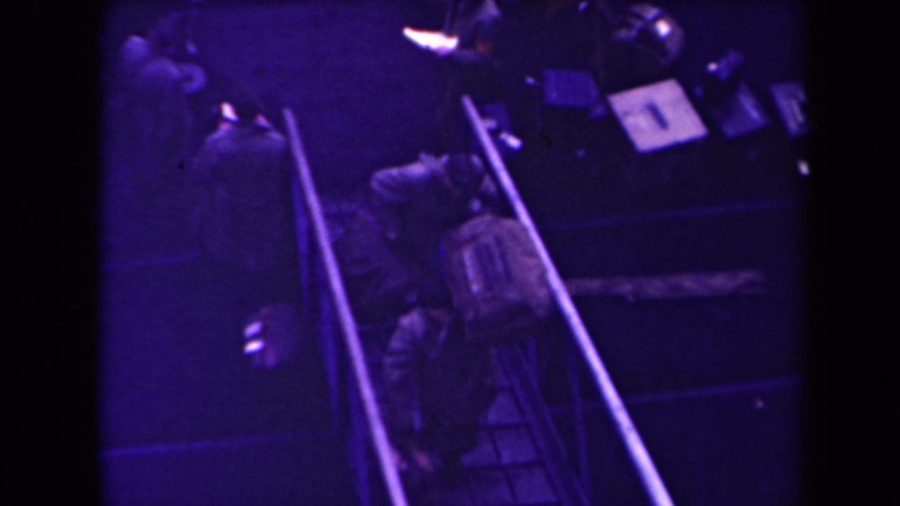 Soldiers with gear continue down the ramp beside railings and dark floor areas.
