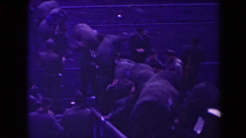 A closer handheld view shows uniformed men pressed around a gangway, consistent with the clip's military boarding scene.