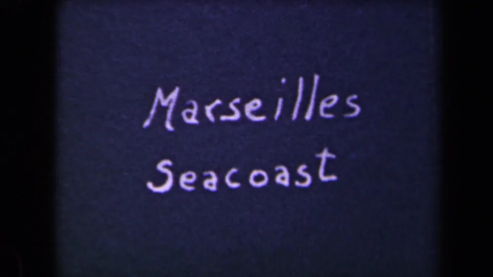 Another 8mm frame of the handwritten Marseilles Seacoast card, with visible grain and dark film borders.