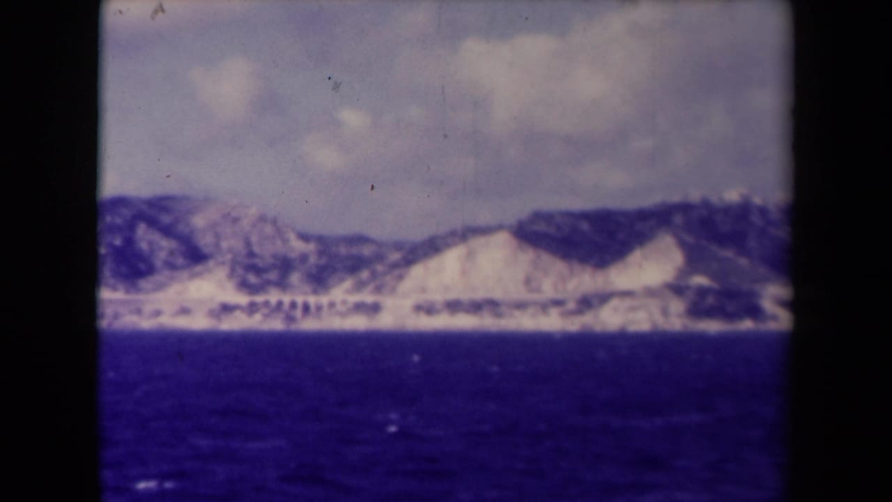 Distant pale mountains and dark ridges seen across open water.