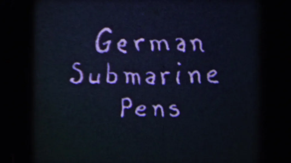 1940s 8mm frame with a handwritten title card reading German Submarine Pens against a dark background.
