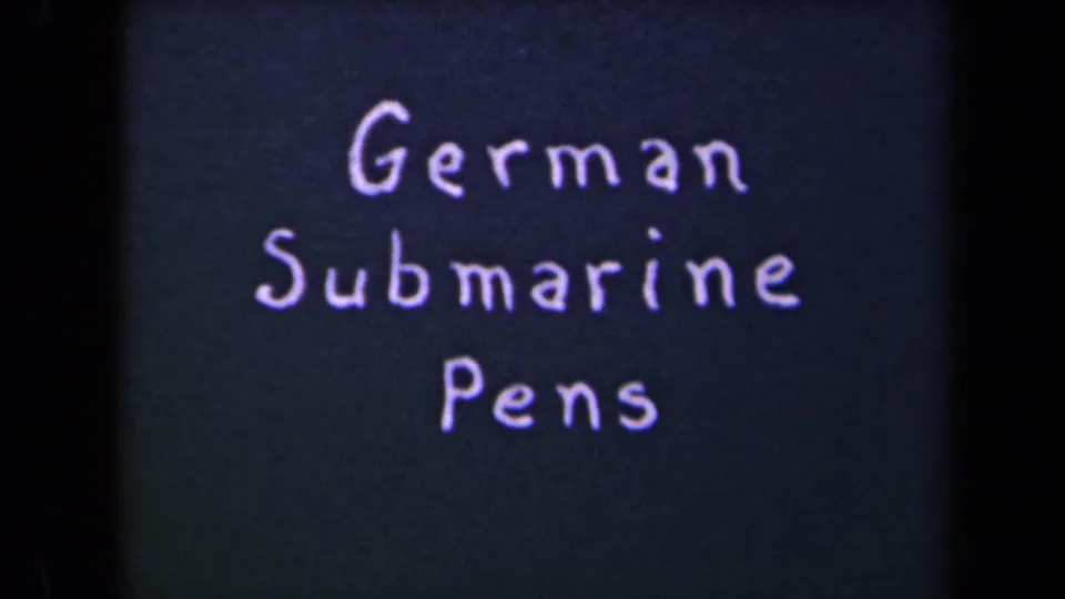 Handwritten German Submarine Pens title card on dark 8mm film, with visible grain and soft focus.