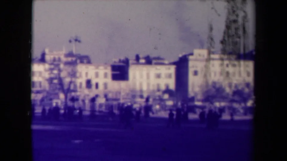 1945 French city street view with pedestrians crossing or gathering near multi-story buildings and bare street trees.