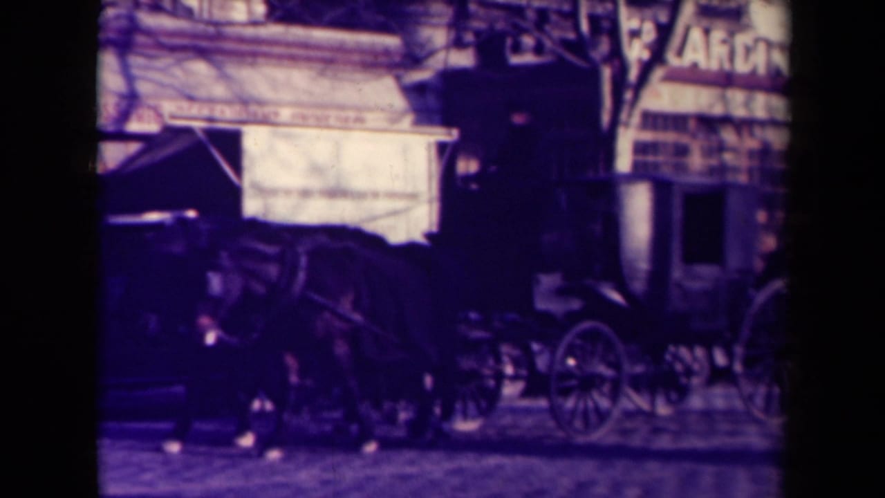 Horse-drawn carriage and carriage wheels visible on a 1945 French city street, with storefront awnings and pedestrians nearby.