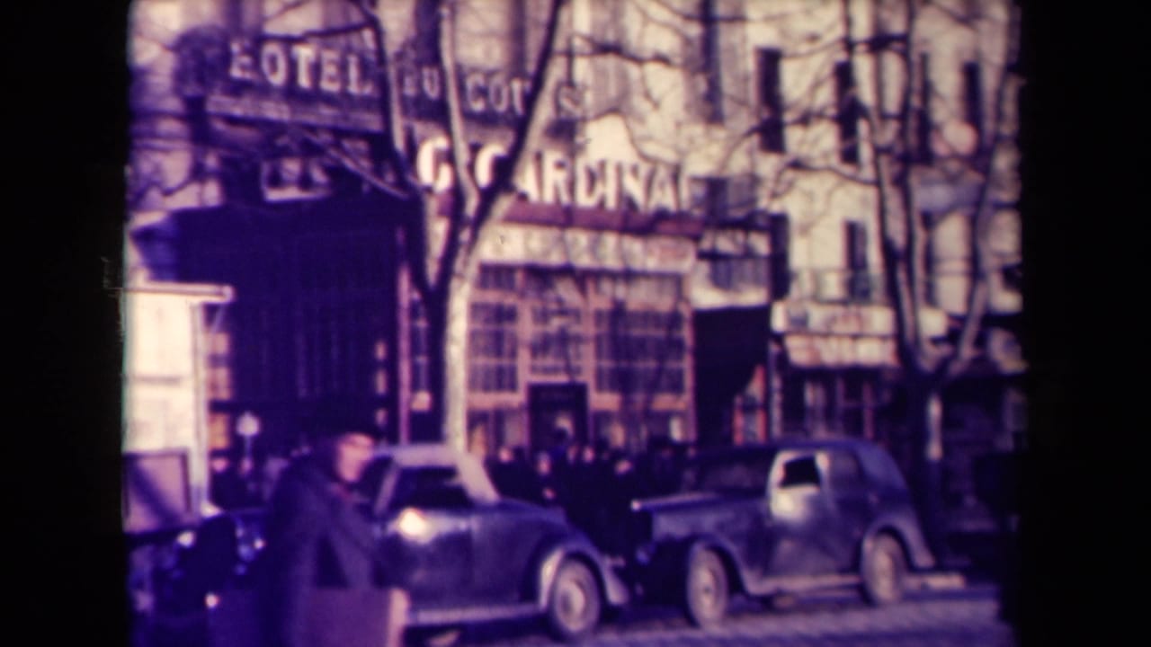 Pedestrians and rounded vintage cars outside a building with hotel and CARDINAL signage.