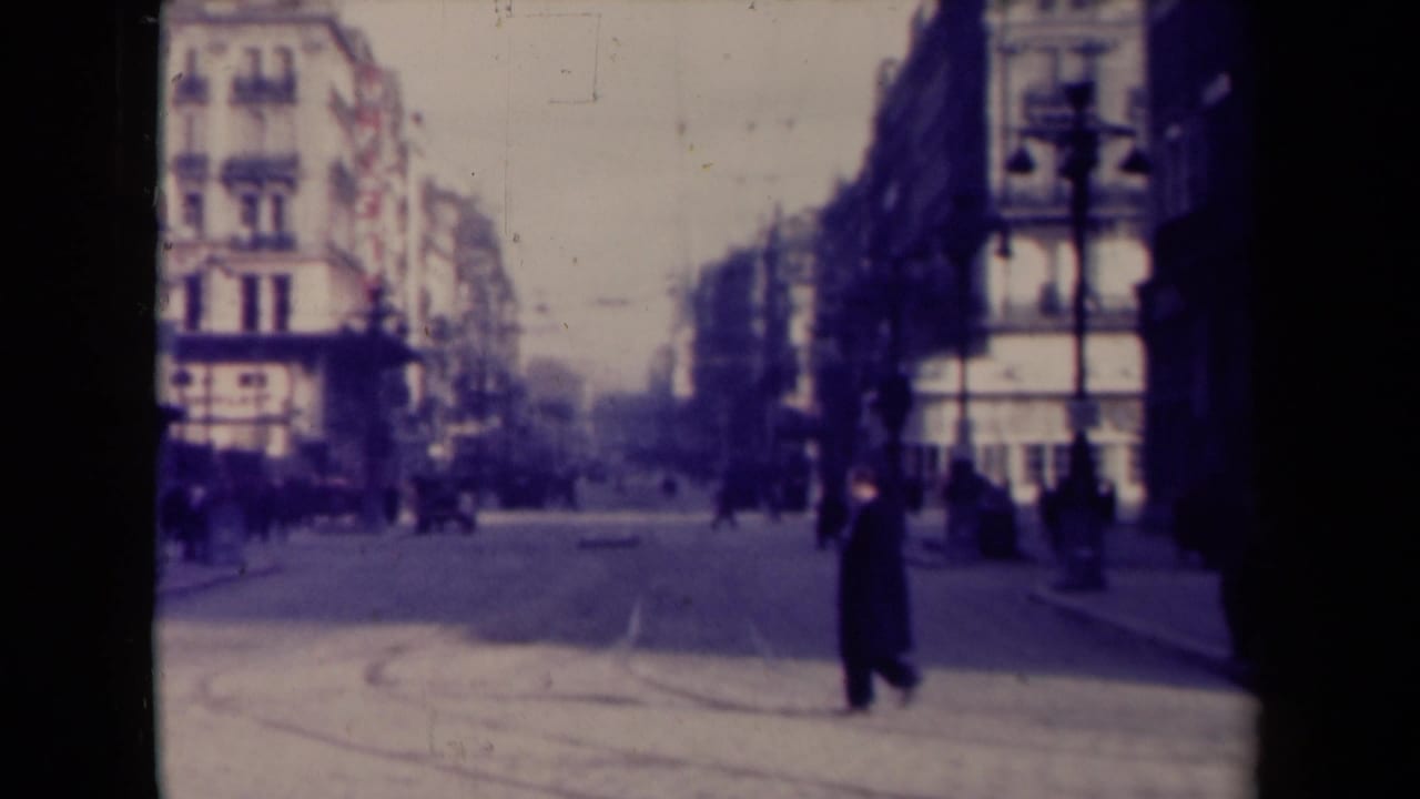 1940s France street scene with a dark-coated pedestrian crossing in the foreground and other people along the sidewalks.