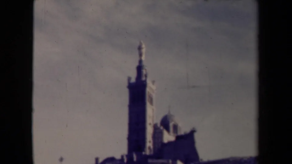 1945 France frame showing the religious tower and chapel from below, softened by faded 8mm color and film wear.