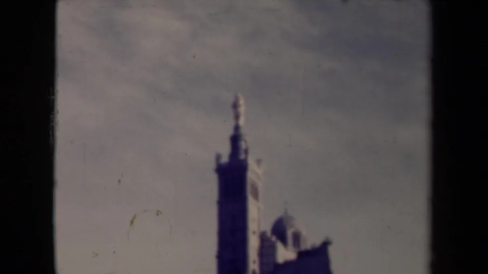 Faded France 8mm frame with the tall tower and adjacent domed structure visible through dark film borders.