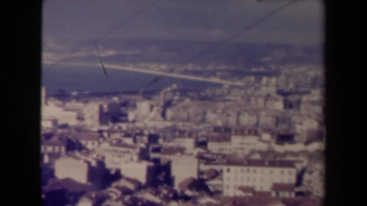 High-angle city panorama with waterfront, bridge-like line, and blurred buildings.