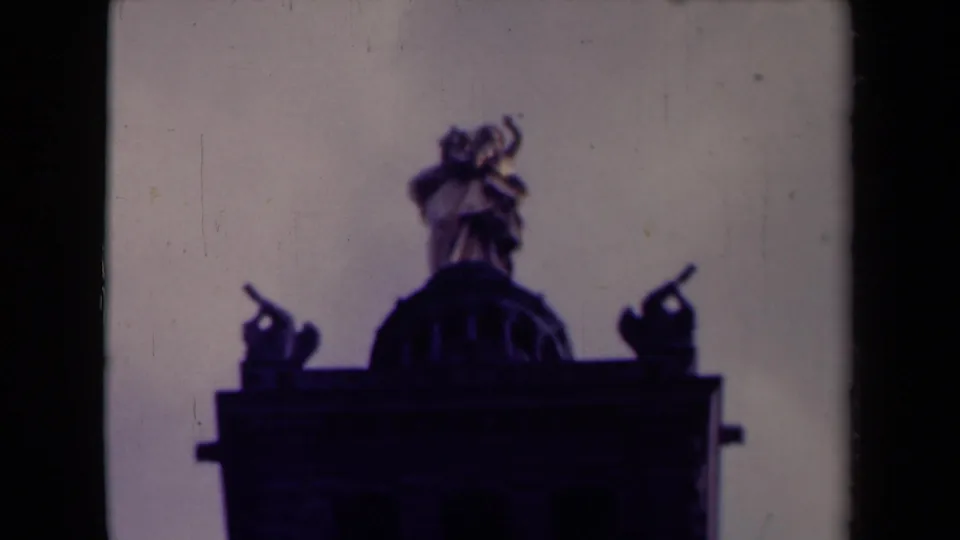 1945 France home-movie frame showing dark rooftop sculpture and a domed architectural feature silhouetted against a pale sky.