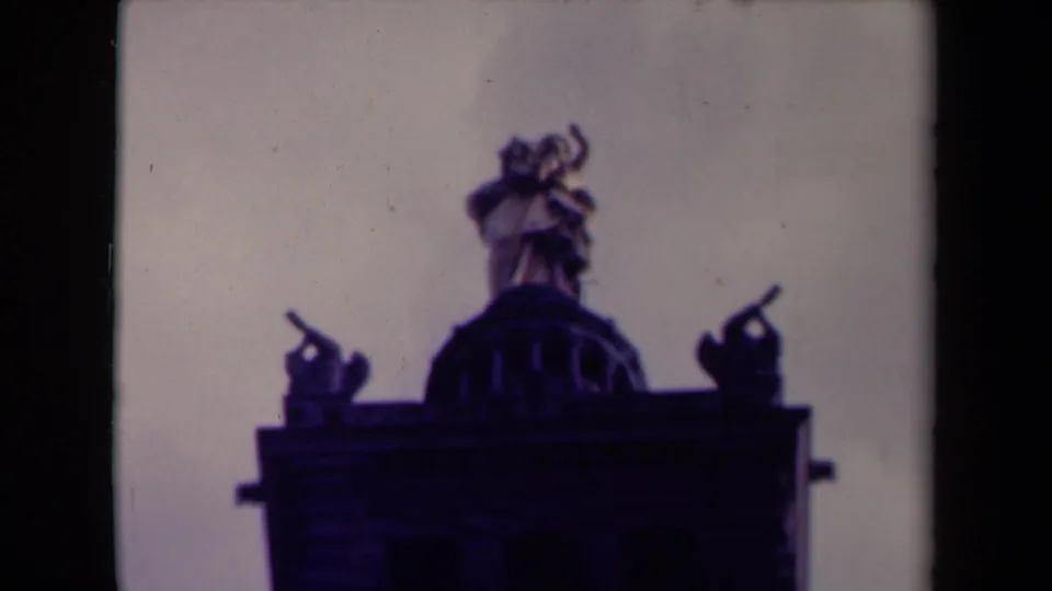 1945 France home-movie view of rooftop statuary and a domed detail, rendered in soft purple-blue film tones.