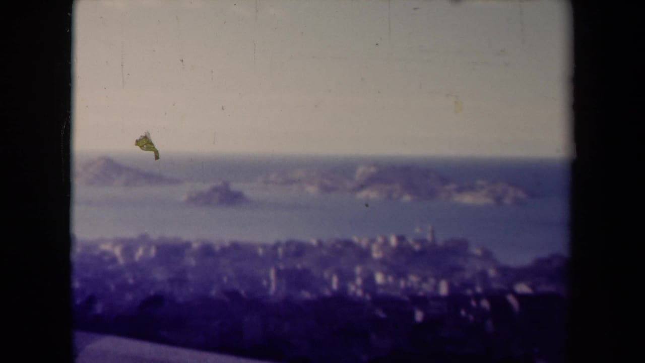 1945 France 8mm view of offshore rocky islands and a coastal city, with dust specks and soft archival color.