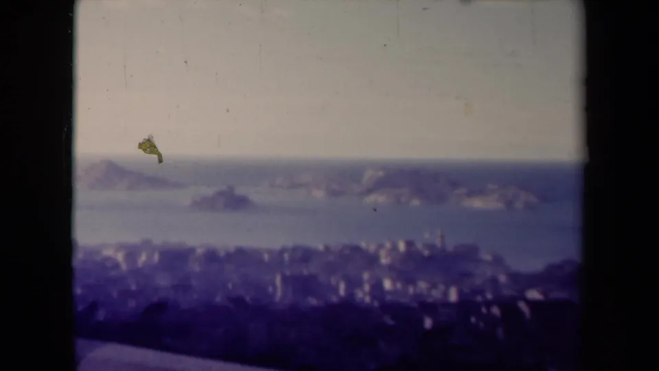 1945 France 8mm view of offshore rocky islands and a coastal city, with dust specks and soft archival color.