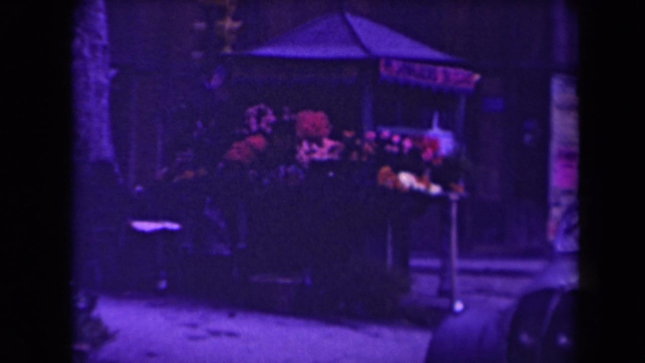 Shadowed canopied stall with colorful goods beside a narrow passage.