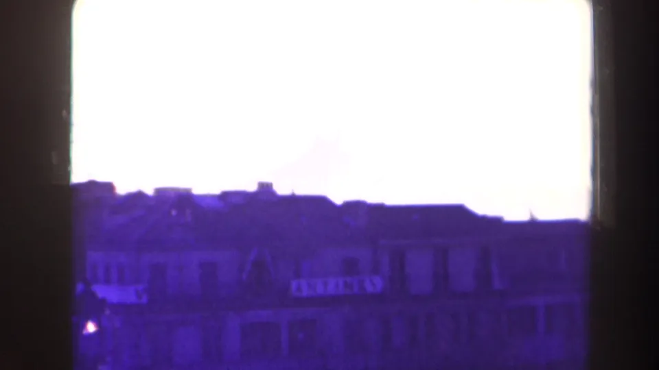 Overexposed 1940s France home-movie frame showing a city roofline and building facades in silhouette.