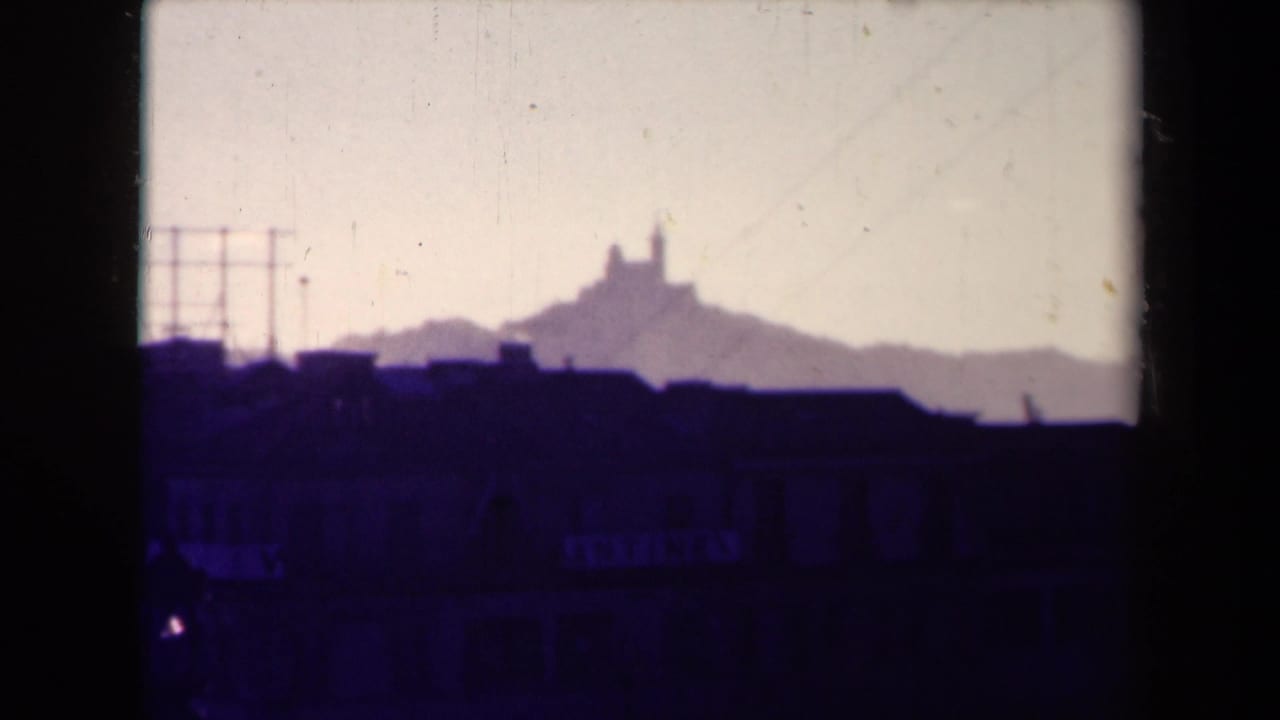 Distant hilltop landmark silhouetted beyond dark city rooftops and rooftop aerials.