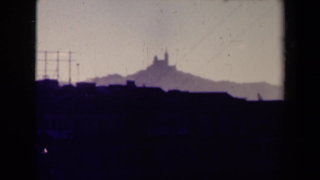 Hazy city skyline with a silhouetted hilltop landmark and dark roofline in the foreground.