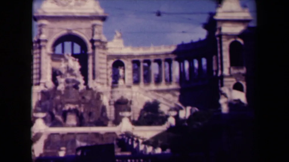 1945 France 8mm frame showing an ornate stone colonnade and central arched facade partly blocked by dark foreground shadow.