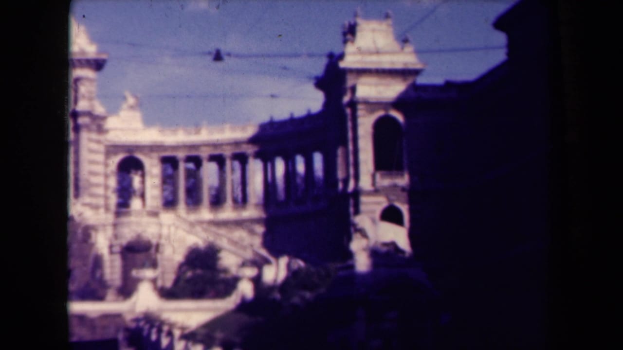 Ornate building and fountain seen through dark film borders with a shaded right side.