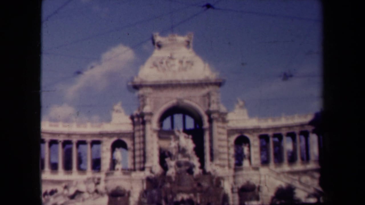 Soft 8mm view of an ornate building facade with arches and a central fountain or sculpture.