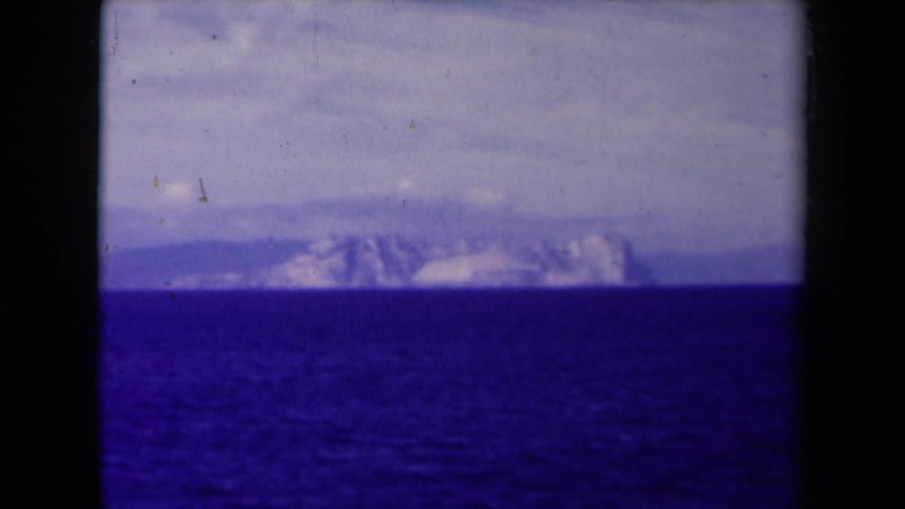 Hazy mountain range on the horizon beyond open water and clouds.