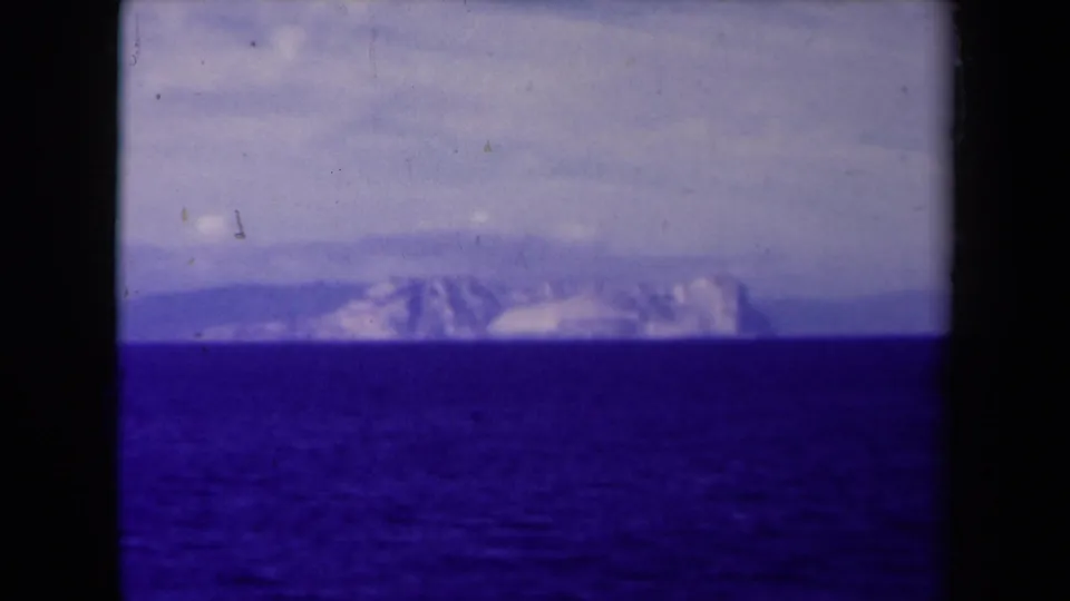 A boat-shot 8mm view from France in 1945 appears to hold on distant snow-bright mountains across a deep blue sea.