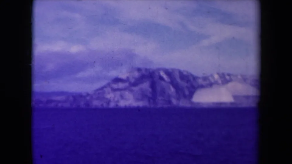 1945 France coastal landscape showing a snow-covered headland across water, recorded on soft, color-shifted 8mm film.