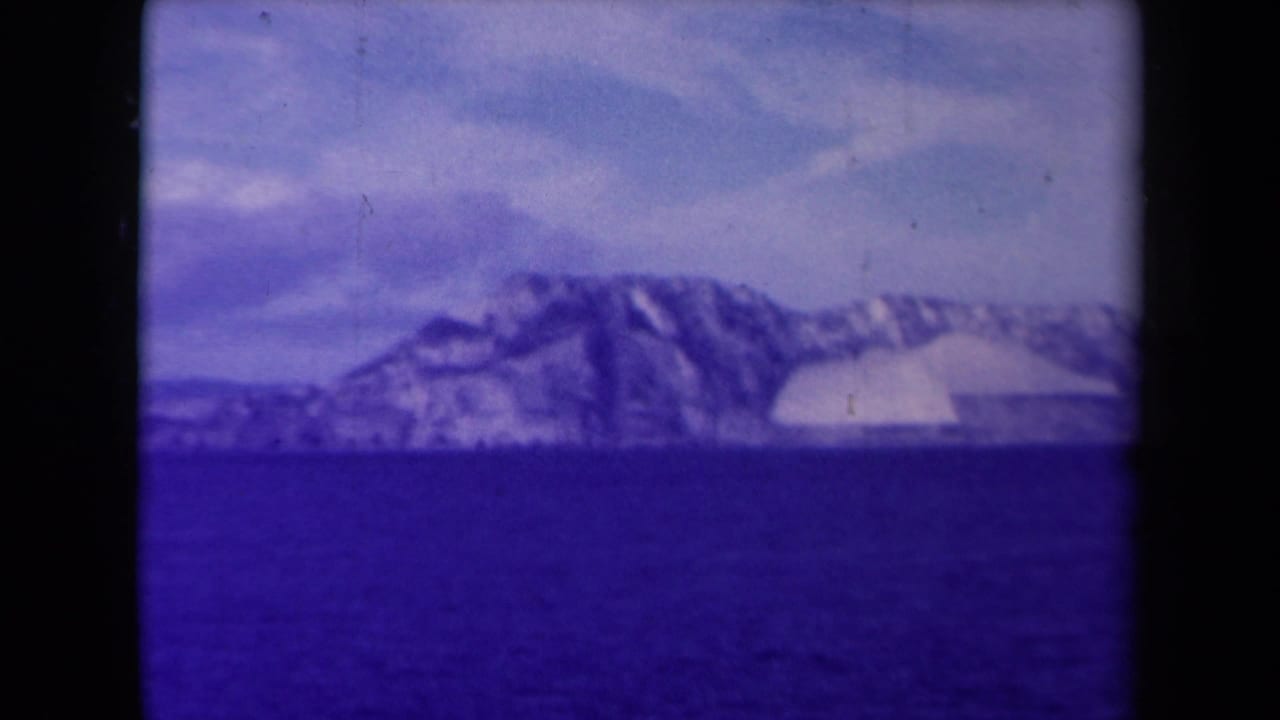 Distant icy shoreline and dark water seen through an 8mm film frame.