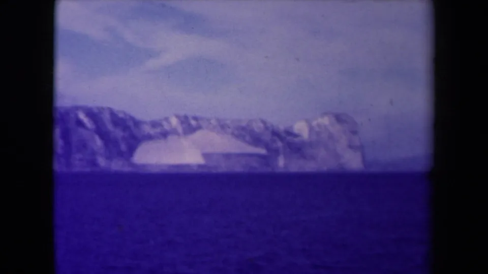 End frame of a 1945 France 8mm coastal view, with a glacier-like shoreline across the water and strong blue-purple film cast.