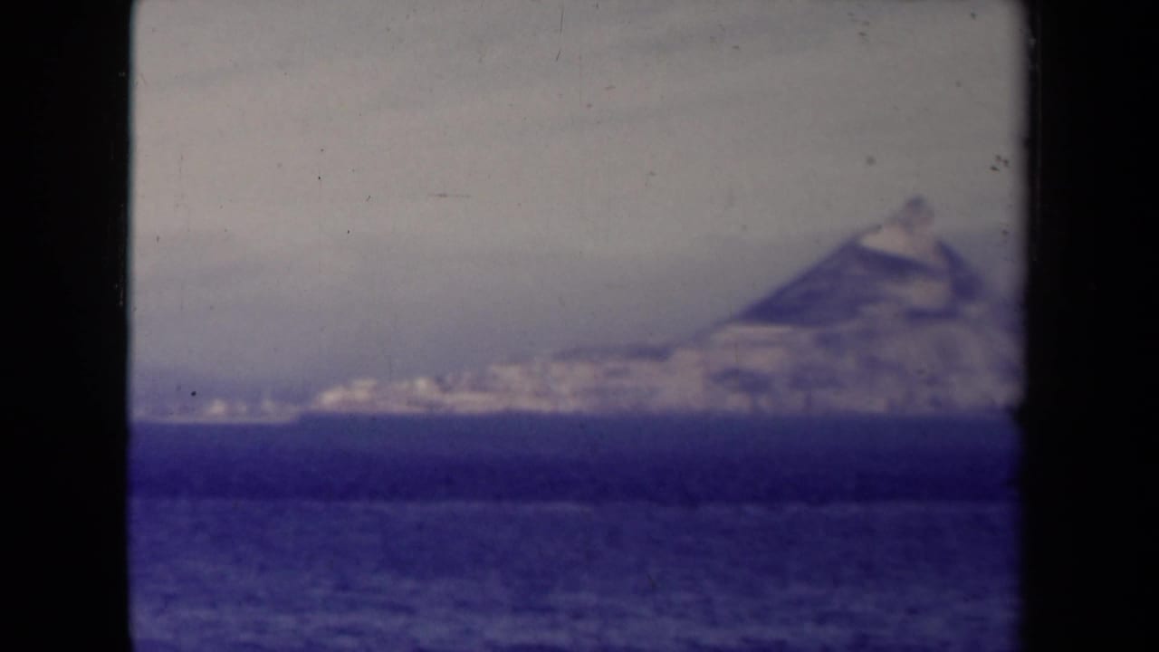 Soft distant peak or iceberg-like mass beyond a dark blue sea horizon.