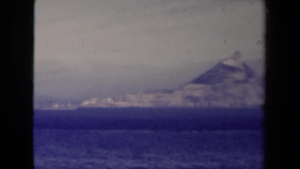 France-labeled 1945 home-movie frame with a blurred distant peak or iceberg-like mass across open water.