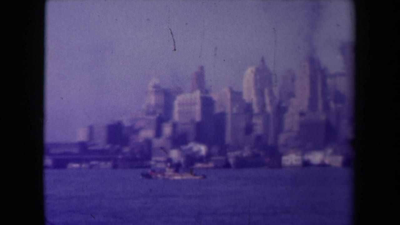 Urban waterfront skyline with tall buildings beyond open water.