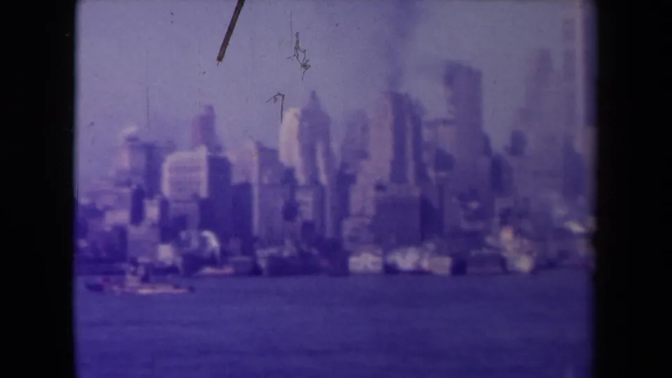 Soft, purple-shifted 8mm view of dense waterfront buildings in France, with water in the foreground and film marks visible.