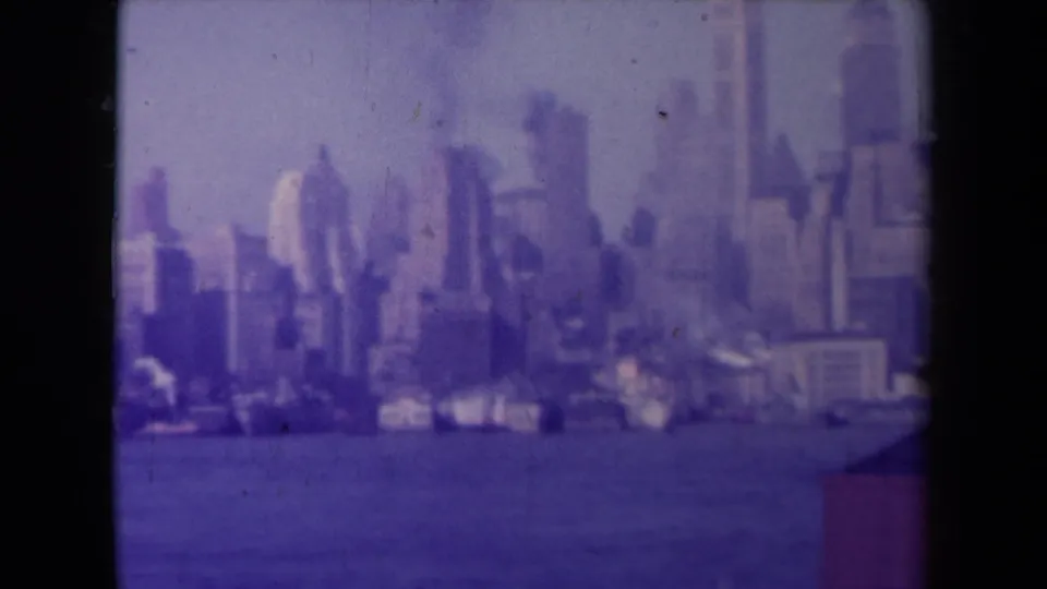 1945 France 8mm frame of a waterfront skyline across water, with a dark film border and a small structure edge at lower right.