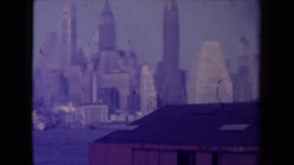 France-attributed 1945 8mm frame showing a distant hazy city skyline with a dark roofline in the foreground and visible film-edge shadowing.