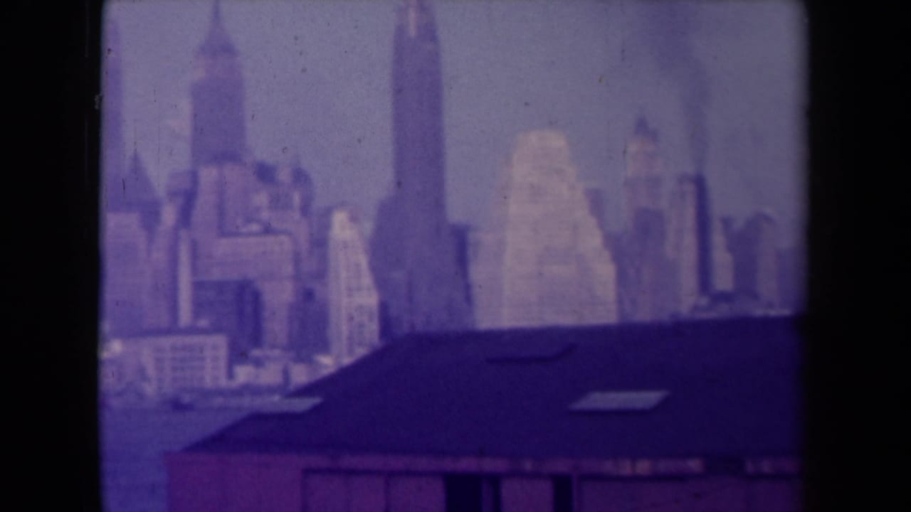 Soft purple skyline view with tall buildings behind a dark roof in the foreground.