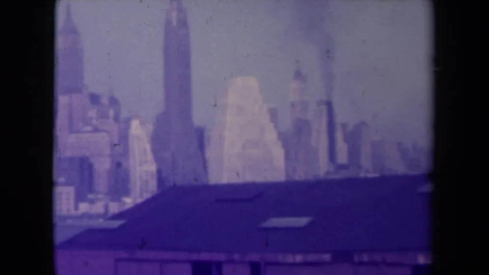 France-attributed 1945 8mm frame showing a blurred urban skyline behind a dark sloping roof, with strong purple color fading.
