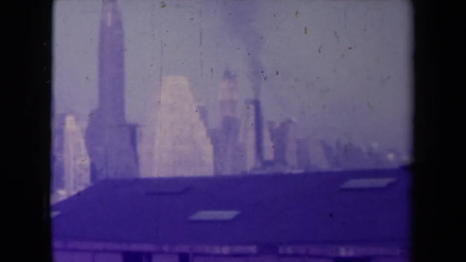 France-attributed 1945 8mm frame of a hazy city skyline and foreground roofline, softened by age-related color shift and surface marks.