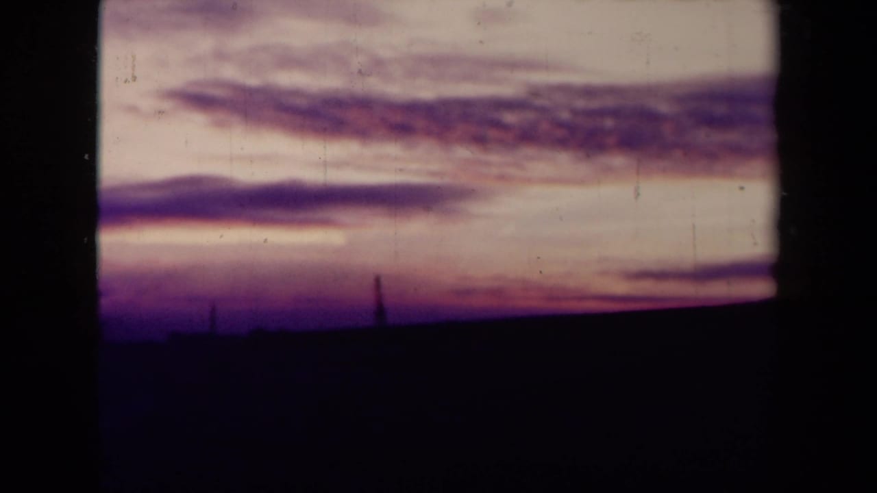 Soft sunset clouds over a dark field, framed by black 8mm contact-sheet borders.