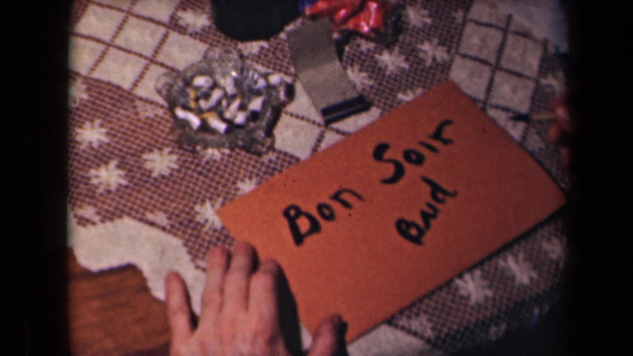 The final frame shows the orange envelope with Bon Soir and additional black writing on a patterned table beside a glass ashtray.