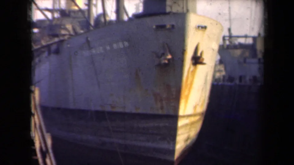 1946 Netherlands 8mm frame showing the bow of the George W. Gibbs at dock, with rust streaks and rigging behind it.